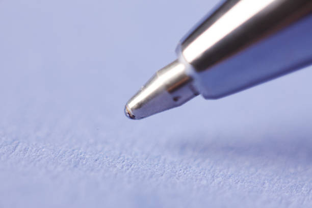 An extreme close-up of the nib of a silver ballpoint pen