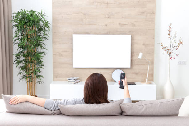 istock Young woman watching TV in the room. white empty screen for design 1170740868