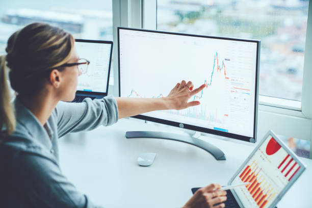 la donna d'affari studia il mercato finanziario per calcolare possibili rischi e profitti. economista femminile che contabilizza denaro con grafici statistici che puntano sullo schermo del computer sul desktop. quotazioni in cambio - technical analysis foto e immagini stock