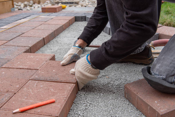 istock Installing paver bricks for patio in backyard. A workman's gloved hands use a hammer to place stone pavers. 1170742301
