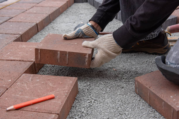 Instalando tijolos paver para o pátio no quintal. As mãos gloved de um trabalhador usam um martelo para coloc pavers de pedra. - foto de acervo