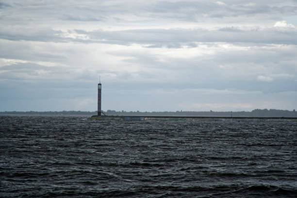 istock Beacon and pier on river calm after storm and strong wind. Lighthouse in the middle. Enhanced sky. 1170742457