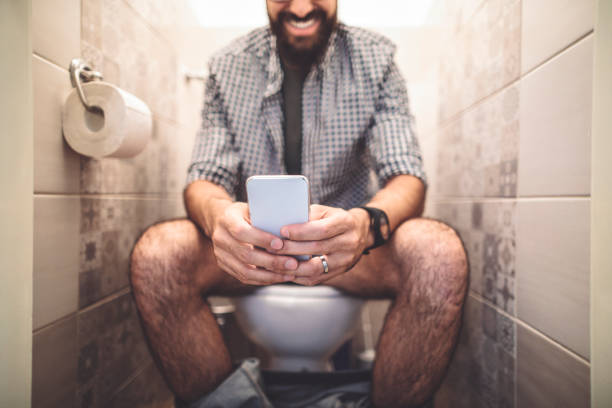 uomo che usa uno smartphone mentre è seduto in bagno - indian culture business businessman financial advisor foto e immagini stock