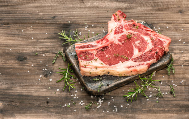 Raw beef meat with herbs and spices on wooden background