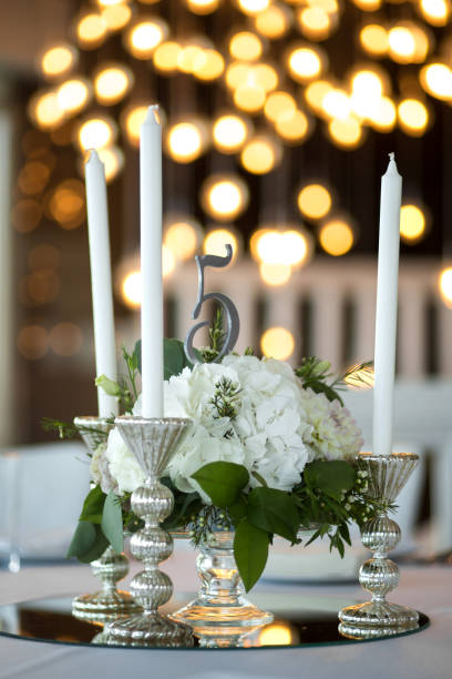 istock Wedding table setting is decorated with fresh flowers and white candles. Wedding floristry. Bouquet with roses, hydrangea and eustoma. On the background blur are burning garlands with light bulbs 1170746251
