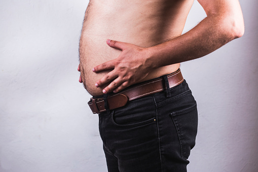 Hombre tocando su vientre gordo sobre fondo blanco - Hombre gordo sobrepeso mostrar vientre photo