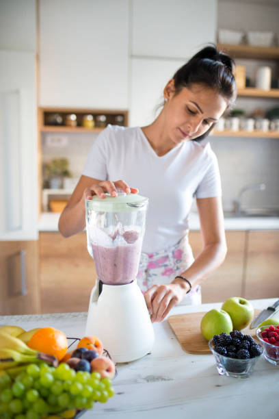 istock Smiling woman making smoothie 1170747512