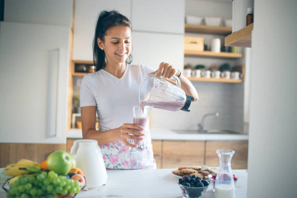istock Smiling woman making smoothie 1170747601