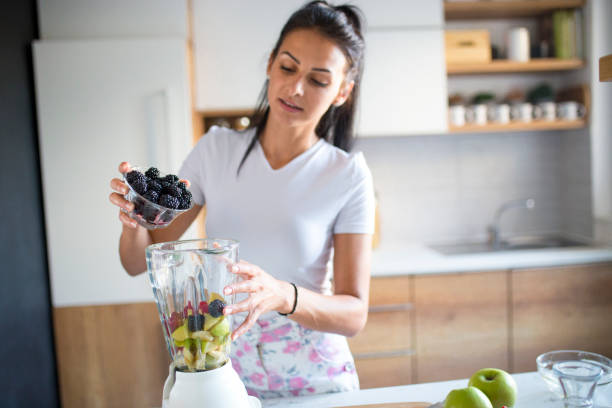 istock Smiling woman making smoothie 1170749006