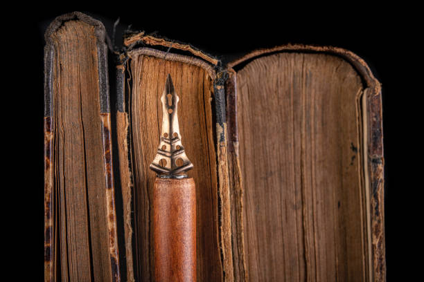 An old nib for writing in ink on a dark table. Antique calligraphy accessories. Black background.