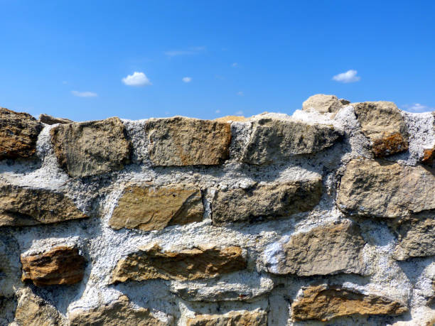 istock grey and brown stone wall detail under blue sky and small fluffy clouds 1170751962