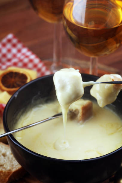 istock Gourmet Swiss fondue dinner on a winter evening with assorted cheeses on a board alongside a heated pot of cheese fondue with two forks dipping 1170754232