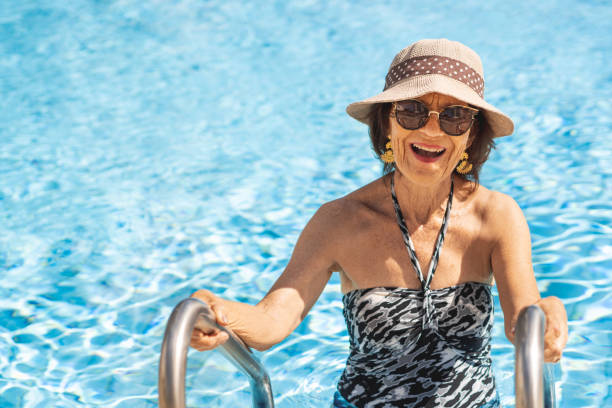 donna rossa anziana che esce dalla piscina - swimwear women swimming pool people foto e immagini stock