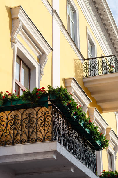 istock Black ornate wrought iron balcony decorated with flowers. Boxes with red geraniums. Bottom side view 1170755863