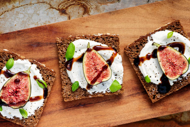 Fresh figs, ricotta cheese, fresh basil on rye bread with balsamic vinegar overhead view.