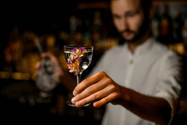 istock Attractive blurred bartender serving a cocktail in the glass decorated with flowers 1170757962