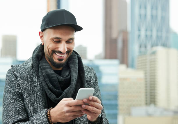 Always making new connections Shot of happy young man using smart phone outdoors in the city north african ethnicity stock pictures, royalty-free photos & images