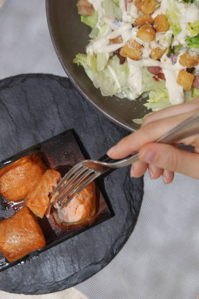 Woman having tuna caesar salad for lunch Woman having tuna caesar salad for lunch caesar salad food salad tuna stock pictures, royalty-free photos & images