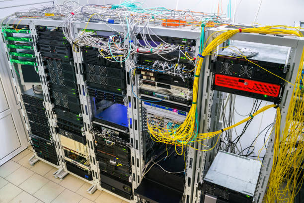 Many wires intertwine on top of server cabinets. Racks with Internet telecommunications equipment are in the server room. Modern computing data center view from above.