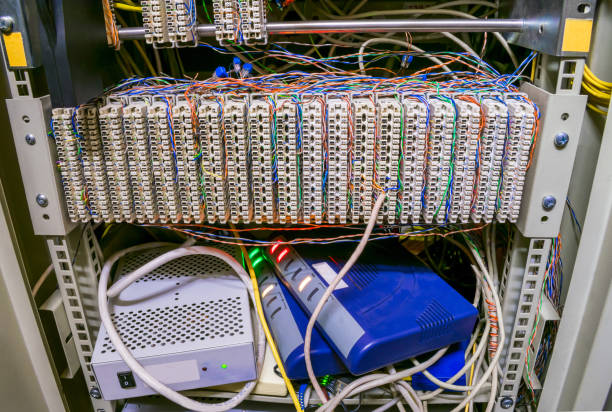 istock Communication patch panel for ip telephony. Modems and switches are in the datacenter server room box. The front panel of a telecommunications cabinet with random interweaving of wires 1170763182