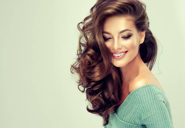 Toothy smile on the face of young, brown haired woman with voluminous hair. stock photo