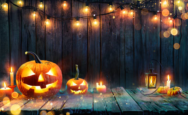 хэллоуин - джек о'фонари - свечи и струнные огни на деревянном столе - spooky stuff фотографии стоковые фото и изображения
