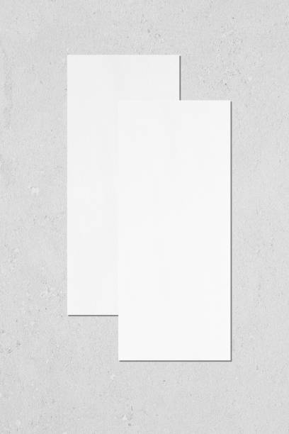 istock Two empty white vertical rectangle price-list or menu mockups lying on top of each other on grey concrete background 1170768003