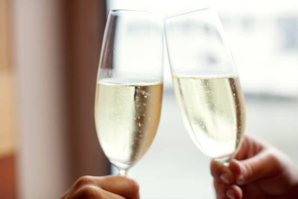 Clinking glasses with champagne in the background of a winter forest.