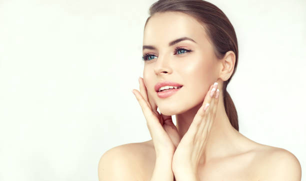 retrato de mujer joven con piel limpia y fresca y maquillaje suave y delicado. la mujer está tocando con ternura la cara. - spa treatment fotos fotografías e imágenes de stock