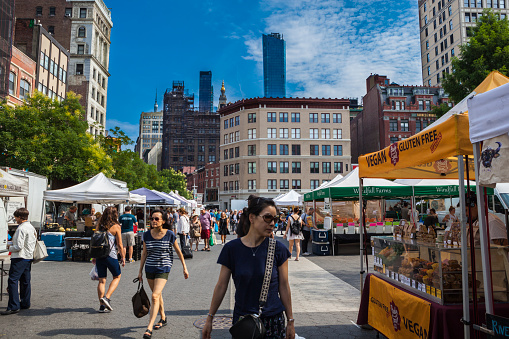 New York, United States - August 21, 2019: People walking and shopping at the Union Square Greenmarket. This farmers market located in Union Square Park just above 14th street in New York City. At this market, they are regional farmers and many food products.