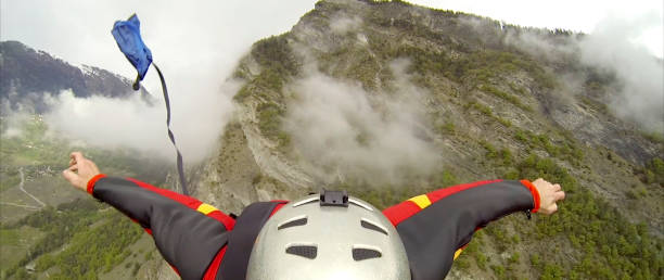 pov of wingsuit flier releasing parachute mid air - mountain drop europe switzerland imagens e fotografias de stock