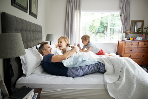 Shot of kids playing with their parents on bed at home