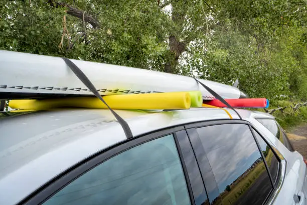 stand up paddleboard on a rental car roof, improvised fitting with straps and swimming pool foam noodles