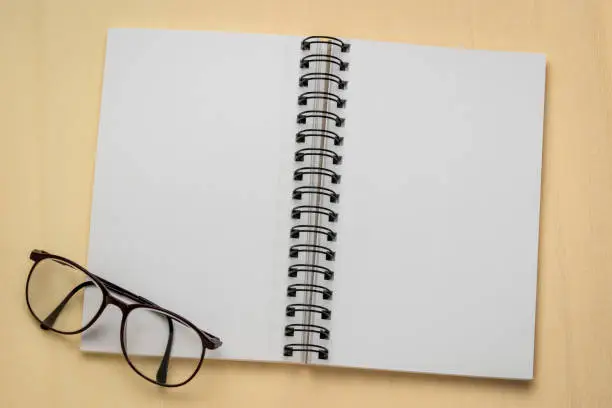 blank spiral art sketchbook with reading glasses against textured crepe paper