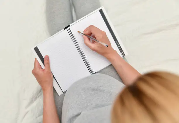 Pregnant woman makes the notes in notebook