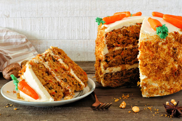 Slice of homemade carrot cake with cream cheese frosting, side view table scene against white wood Slice of homemade carrot cake with cream cheese frosting and fondant carrots. Side view table scene with a white wood background. cream cheese photos stock pictures, royalty-free photos & images