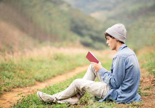 istock young boy reading a book in the park 1170795494