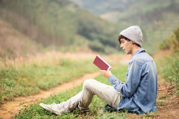istock young boy reading a book in the park 1170795780