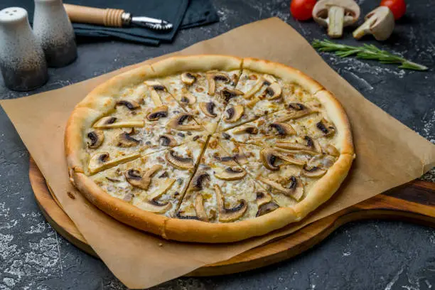 Photo of pizza with mushrooms on dark grey concrete table