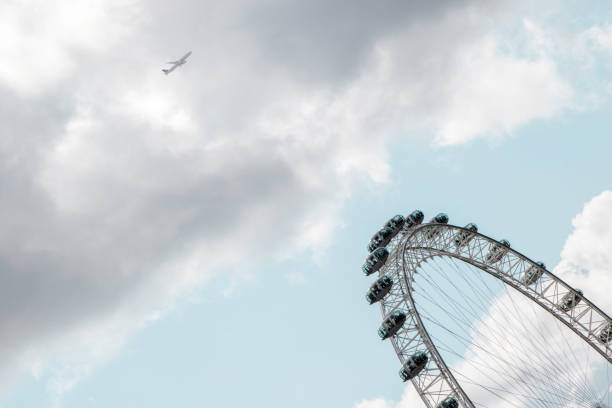 London, England - June 3, 2015 The London Eye, also known as the millennium wheel, on the south bank of the river Thames in London and plane in background.