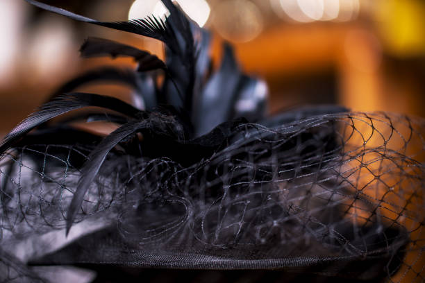 Black Teardrop Funeral Hat with Veil and Feathers on brown background