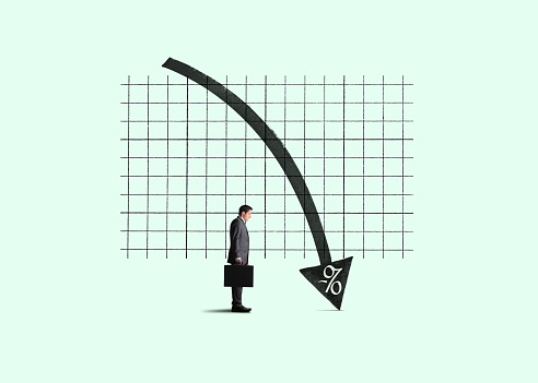 A businessman holding a briefcase stands somewhat disinterested by a chart indicating the concept of negative interest rates.