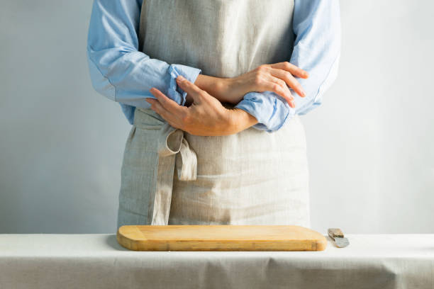 istock Female cook in cotton apron at the kitchen table with cutting board. Rustic natural style. Kinfolk concept. Copy space. 1170818268