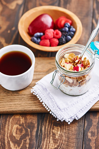Apple and cranberry breakfast cereal served in jar with coffee and fresh fruit