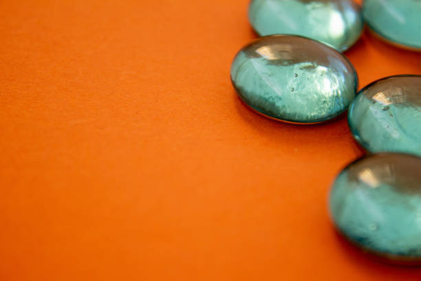 View of Transparent glass pebbles placed on orange background