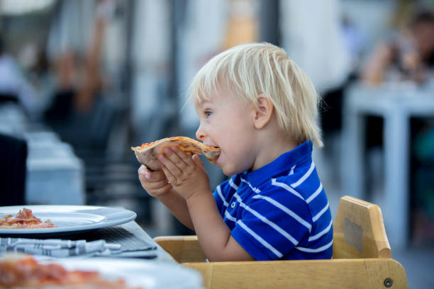 istock Toddler boy, eating pizza on the beach in restaurant 1170825490