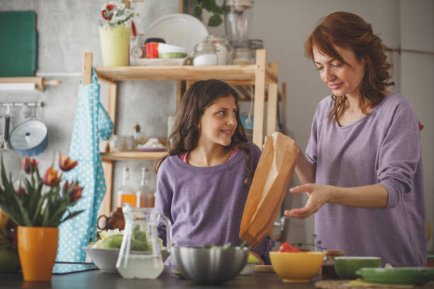 istock Mother packing lunch for her daughter into paper bag 1170825512
