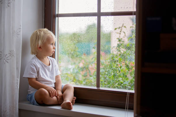 istock Adorable little boy, sitting on window shield, looking through the window on a rainy day 1170827130