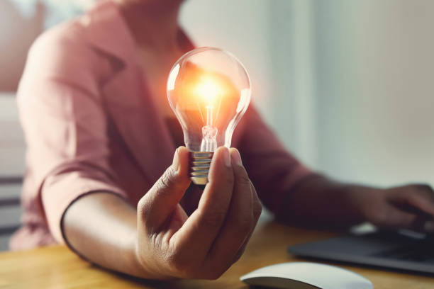 istock hand holding light bulb with using laptop in office. concept saving energy power 1170828071