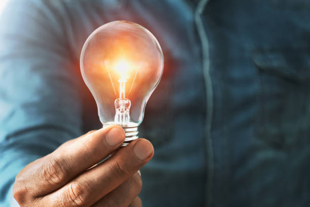 istock businessman hand holding lightbulb with sunshine. concept saving energy power 1170828080